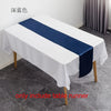 A white tablecloth with a navy blue satin table runner is displayed on a table.