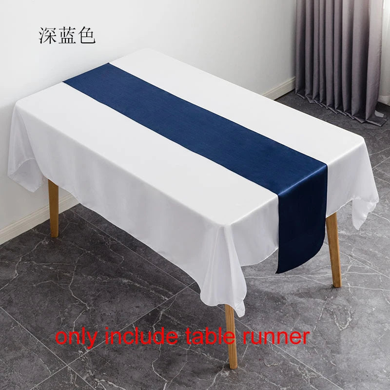 A white tablecloth with a navy blue satin table runner is displayed on a table.