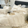 A set of white Korean lace duvet cover and pillowcases with a matching ruffled bedspread.