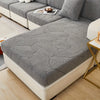 A gray leaf pattern sofa slipcover is displayed on a white sofa with gold accents.