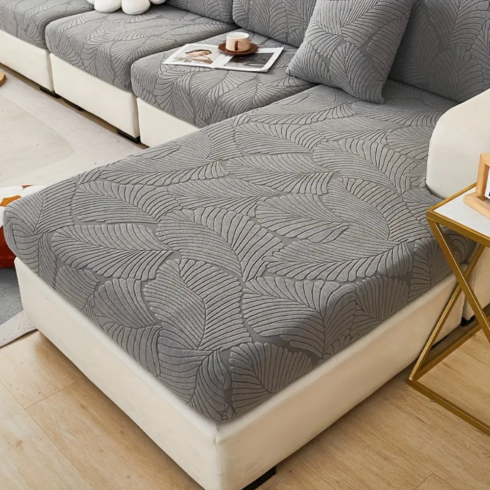 A gray leaf pattern sofa slipcover is displayed on a white sofa with gold accents.