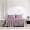A luxury organic bamboo bed sheet set in mauve color draped over a bed.