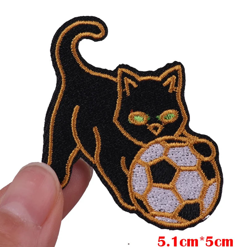 Black cat embroidered patch with glowing green eyes on a soccer ball background
