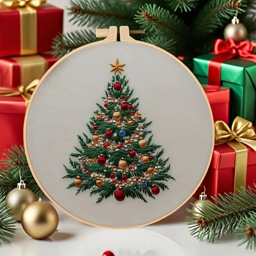 A round wooden embroidery hoop featuring a detailed Christmas tree design with ornaments and gold accents.