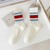 Pair of white crew socks with red and blue horizontal stripes displayed on a white surface.