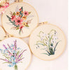 A collection of five embroidery designs featuring floral patterns on light cream fabric.