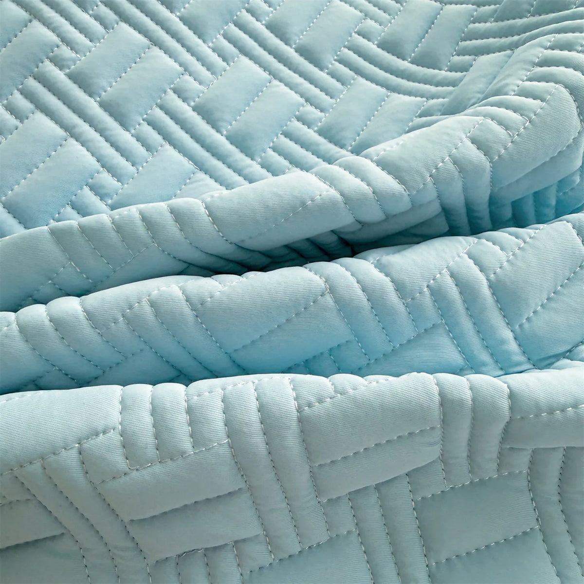 Light blue quilted fitted sheet mattress protector fabric showing various folds and pleats