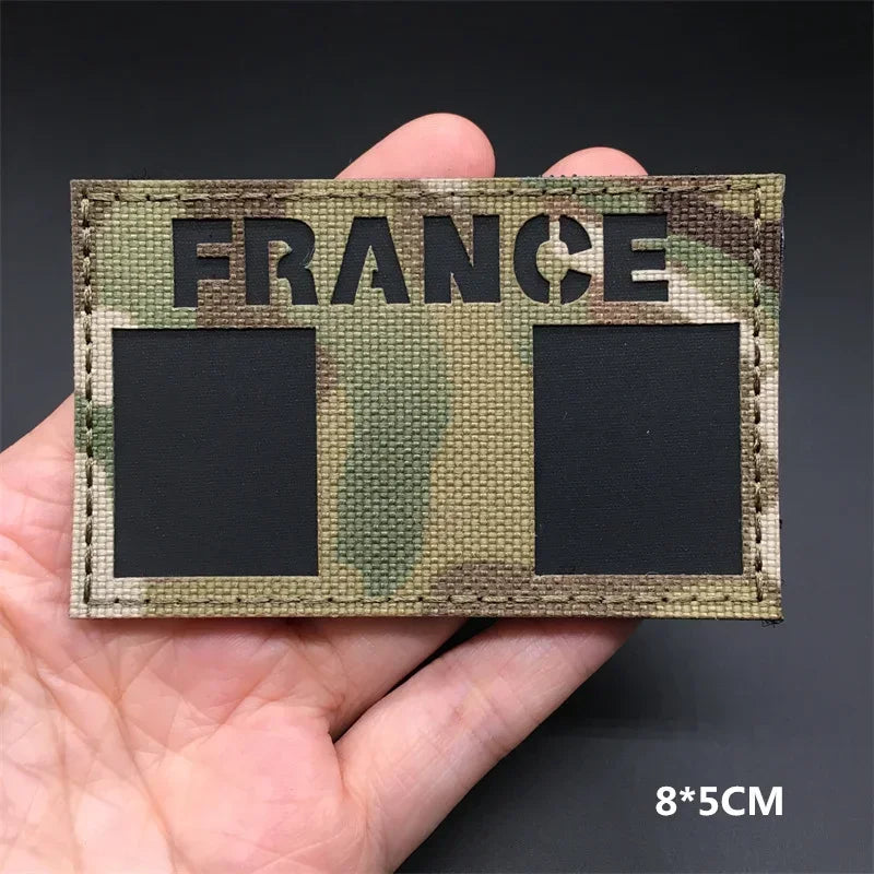 A close-up of a fabric patch featuring the word FRANCE in large letters on a camouflage background.