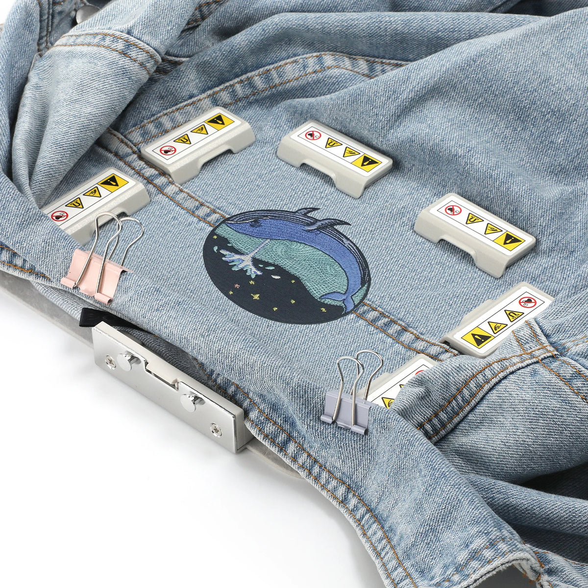 A denim garment shows several magnetic embroidery hoops attached to the fabric.
