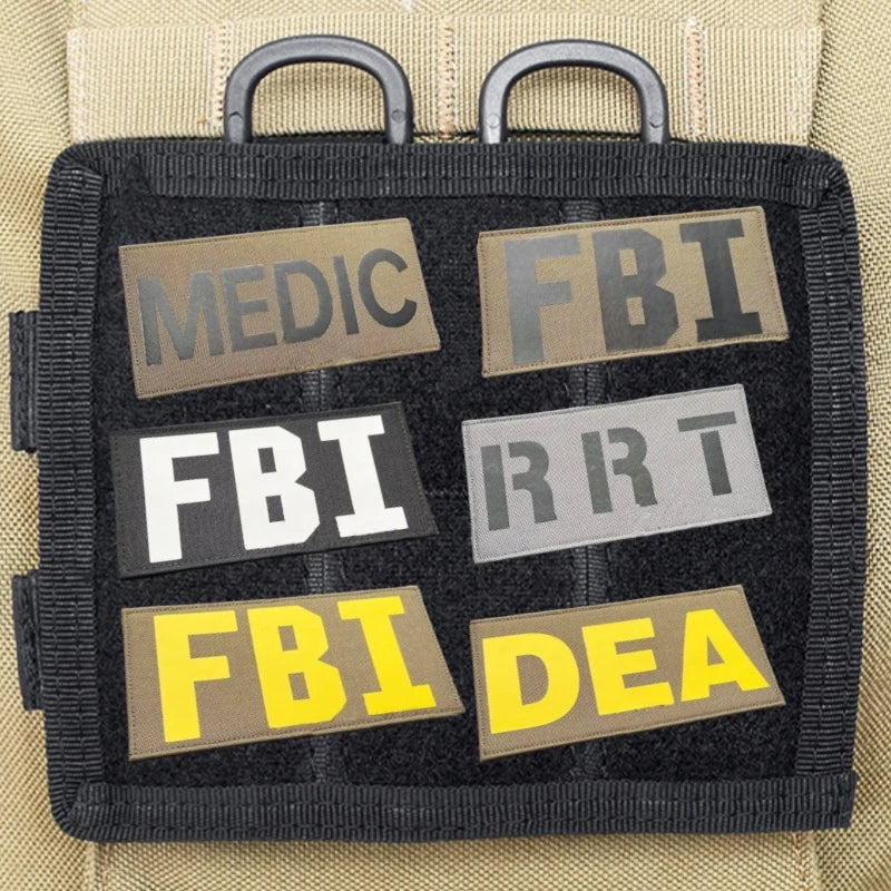 A black tactical hook and loop patch with five rectangular labels featuring acronyms like MEDIC, FBI, and DEA.