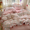 A pink floral bedding set with ruffled pillows and duvet covers is displayed on a bed.