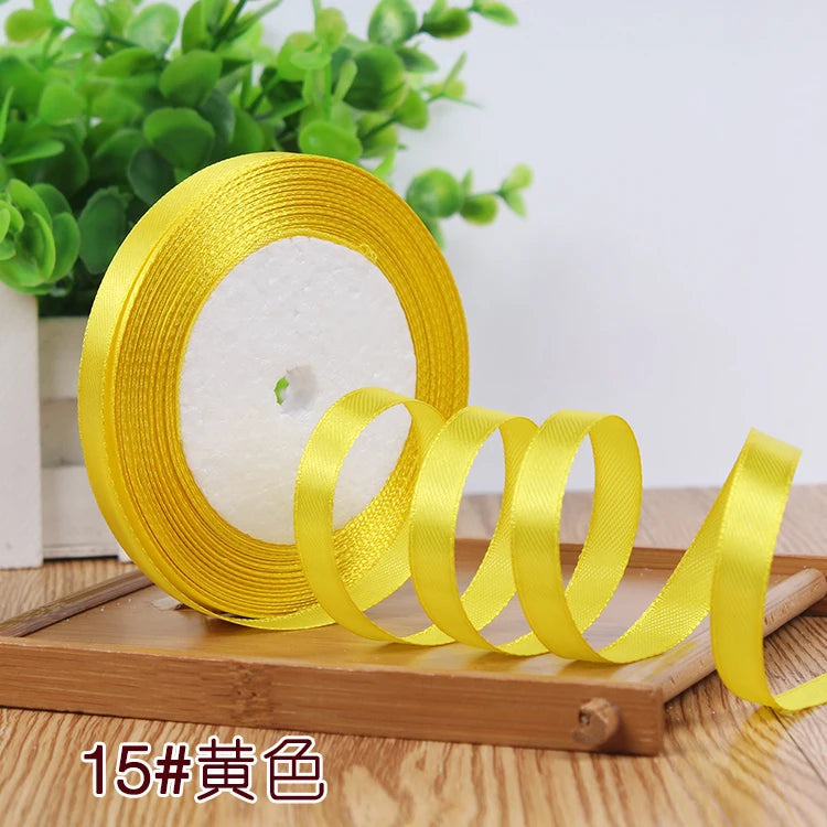 Roll of yellow satin ribbon with a center hole displayed on a wooden surface.