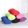 A collection of colorful microbead neck pillows in shades of red, pink, green, blue, and purple resting on a white surface.