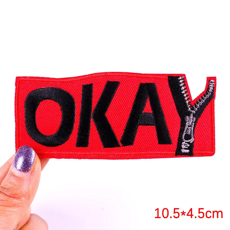 Red embroidered okay patch with black lettering and zipper detail