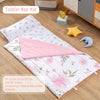 A pink floral toddler nap mat featuring a quilted surface, a pillow, and a blanket on a wooden floor.