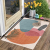 A rectangular kitchen floor mat featuring abstract watercolor shapes in teal, terracotta, and olive green on a wooden floor.