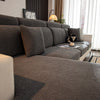 A modern gray stretch sofa seat cushion cover with textured fabric and throw pillows in a living room setting.