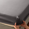 A close-up of a gray soft touch microfiber fitted sheet being held by hands.