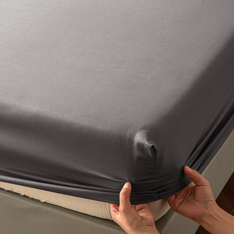 A close-up of a gray soft touch microfiber fitted sheet being held by hands.