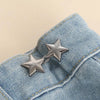 Silver star-shaped brooches clipped onto a light blue denim fabric