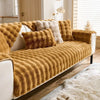 A mustard yellow plush rabbit sofa cushion resting on a white sofa with additional fluffy cushions.