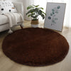 A round, dark brown shaggy area rug placed on a light wooden floor.
