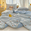 Light blue and white striped quilt with small animal patterns displayed on a bed.