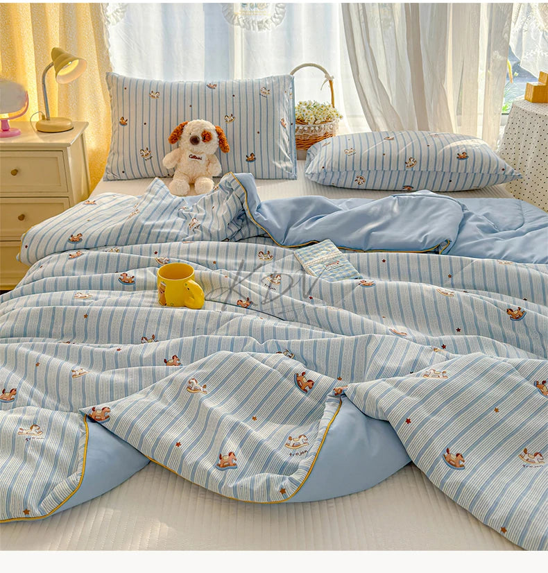 Light blue and white striped quilt with small animal patterns displayed on a bed.