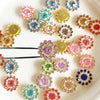 A collection of multicolor sew-on rhinestone crystals in various shades of pink, blue, purple, and gold arranged on a white s