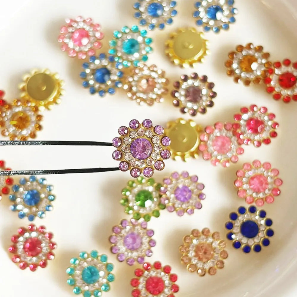 A collection of multicolor sew-on rhinestone crystals in various shades of pink, blue, purple, and gold arranged on a white s