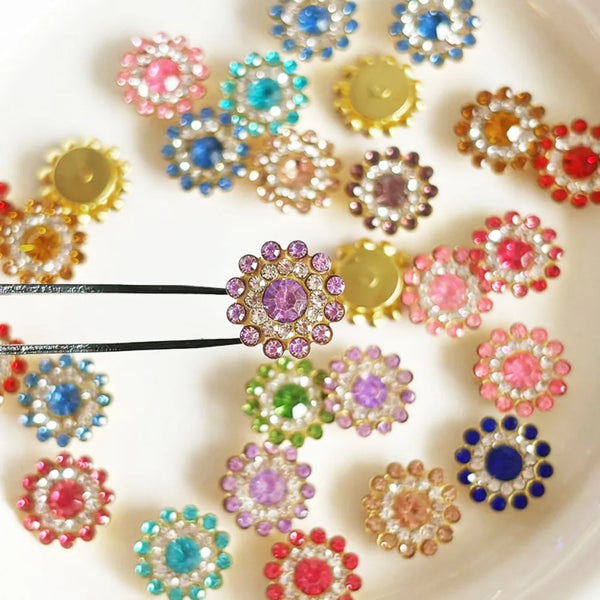 A collection of multicolor sew-on rhinestone crystals in various shades of pink, blue, purple, and gold arranged on a white s