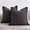 A dark gray textured boucle throw pillow resting on a light-colored sofa.