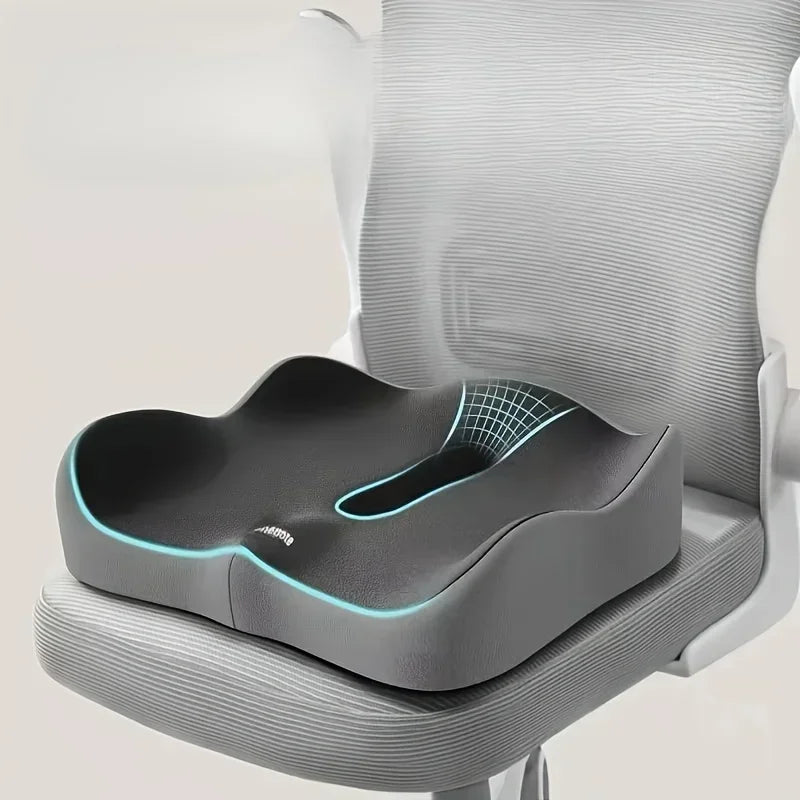 A gray ergonomic memory foam seat cushion is placed on a light gray chair seat.
