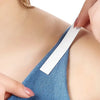 A close-up of a hand applying an invisible self-adhesive lingerie tape to a shoulder area.