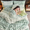 A plush rabbit hair bedding set in mint green and lime green colors with a woman resting on the bed.