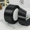 Roll of black satin ribbon with white decorative trim on a white background