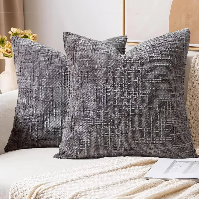 A close-up of a dark gray boucle texture throw pillow cover resting on a white sofa.