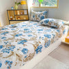 A fitted bed sheet with a blue and brown floral print is displayed on a bed.