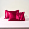 A stack of vibrant magenta satin pillowcases with envelope closures resting on a white table.