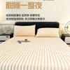 A close-up of thick, ribbed, cream-colored fitted bed sheets on a bed with white pillows.