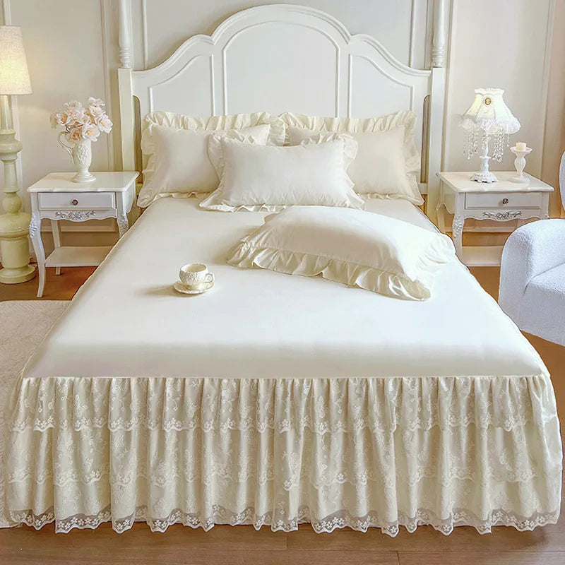 A white bed with a ruffled lace skirt and white linens, flanked by decorative nightstands and a headboard.