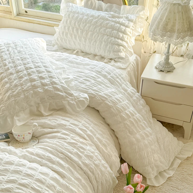 A white lace seersucker duvet cover set displayed on a bed with light yellow curtains.