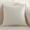 A square, light gray luxury chenille throw pillow cover resting on a beige textured sofa.
