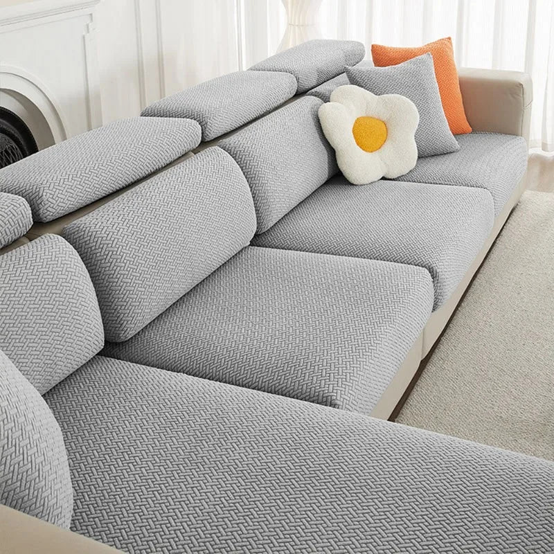 Gray jacquard elastic sofa cushion slipcover with an orange accent pillow on a light-colored sofa.