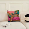 A pink and green cushion cover featuring a cheetah print and tropical plant design on a white sofa.