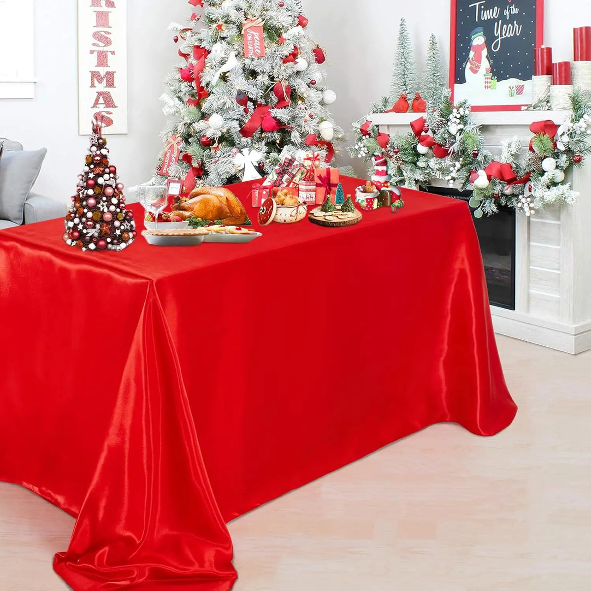 A red satin tablecloth set for elegant dining and party decor featuring Christmas greenery and decorations.