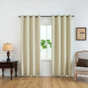 Cream-colored blackout window curtains hanging in a window frame with a wooden table and chair nearby.