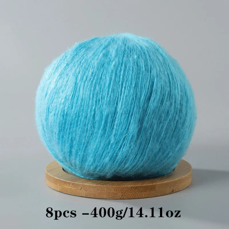 A ball of bright turquoise blue mohair yarn resting on a wooden base.