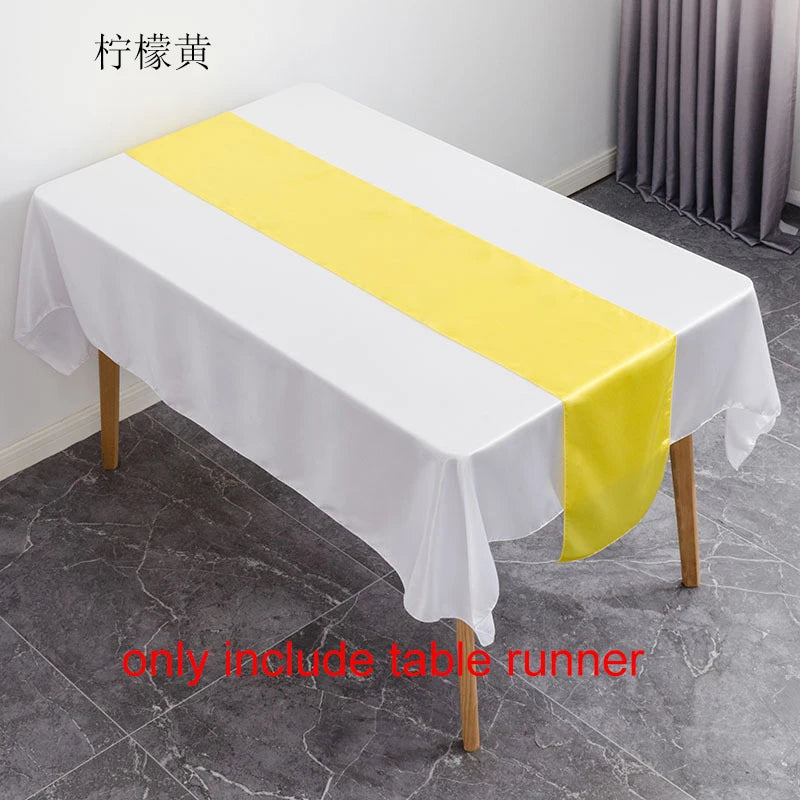 A white tablecloth with a yellow satin table runner is displayed on a table.