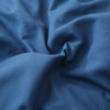 A close-up of a deep blue luxury polyester pillow cover set fabric with soft folds.